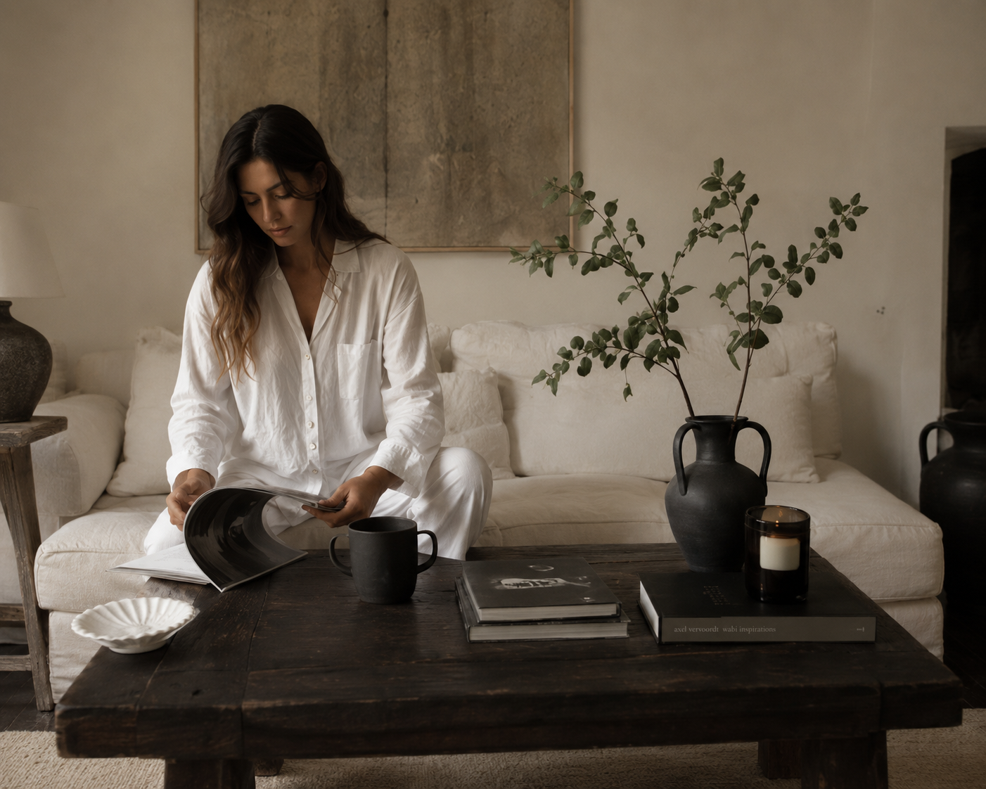 A soft interior, a woman reading among warm neutrals and shadow